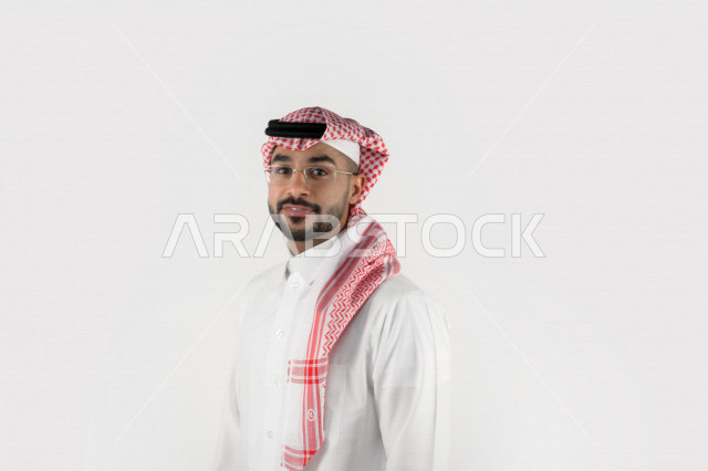 بورتريه لرجل عربي خليجي سعودي يرتدي الزي السعودي التقليدي وينظر إلى الكاميرا، إيماءات وجه ويدين مختلفة، رجل يلبس نظارة طبية، تعبيرات وجه مبتسمة خلفية بيضاء