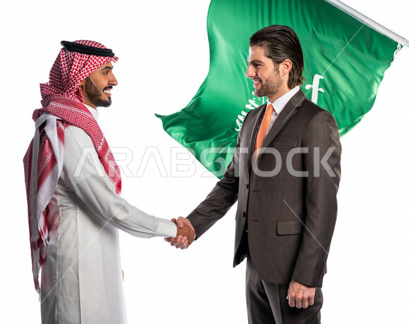 Portrait of a Saudi Arab man shaking hands with a foreign man in a uniform, agreement and partnership on business and commercial projects, business partners, cooperation between companies, work environment, Saudi National Day, Saudi flag illustrated on a