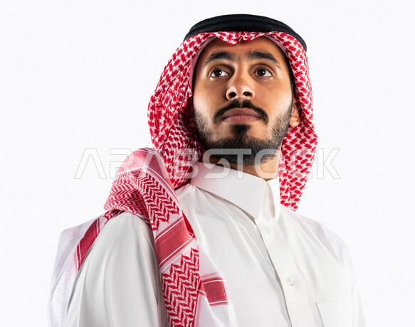بورتريه لرجل سعودي خليجي يقوم بجلسة تصوير ، ينظر لأعلى بإيماءات وجه ويدين مختلفة ، خلفية بيضاء لرجل سعودي مسلم يرتدي زي تقليدي سعودي مع شماغ وعقال