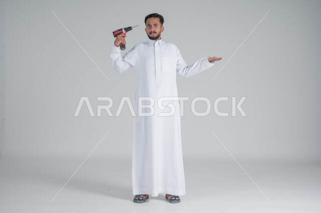 ايماءات التعجب والاستفسار, المهارة و اتقان العمل، استخدام أدوات ومعدات الصيانة لاجراء التصليحات، بورتريه لرجل عربي سعودي خليجي يرتدي الثوب التقليدي ويحمل بيده فرد ثاقب يوجهه نحو رأسه، صورة الجسم بالطول الكامل، خلفية بيضاء