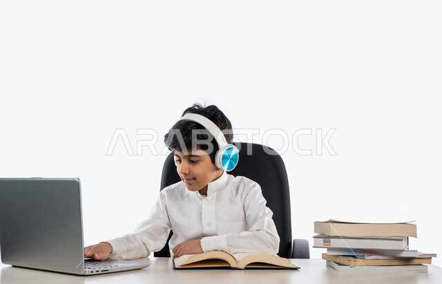 بورتريه لتلميذ عربي خليجي سعودي يرتدي  الثوب السعودي التقليدي و سماعة رأس ، يدرس من خلال منصة تعليمية للتعلم عن بعد ، ايماءات و تعابير للوجه و اليدين مختلفة ، تأدية الواجبات المدرسية ، مفهوم التعليم عبر الانترنت