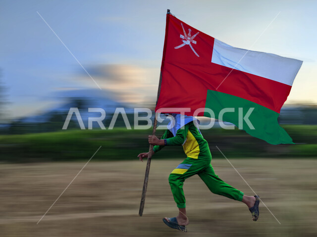 المشاركة بالأعياد والمناسبات الوطنية،, حب الوطن والانتماء إليه، ولد عربي خليجي عماني يحمل بيده علم سلطنة عمان، الاحتفال بذكرى اليوم الوطني العماني 18 نوفمبر،  إحياء ذكرى تأسيس الدولة 1775 م، الركوض في احدى المناطق العمانية، الاعتزاز والفخر بالرموز والراية