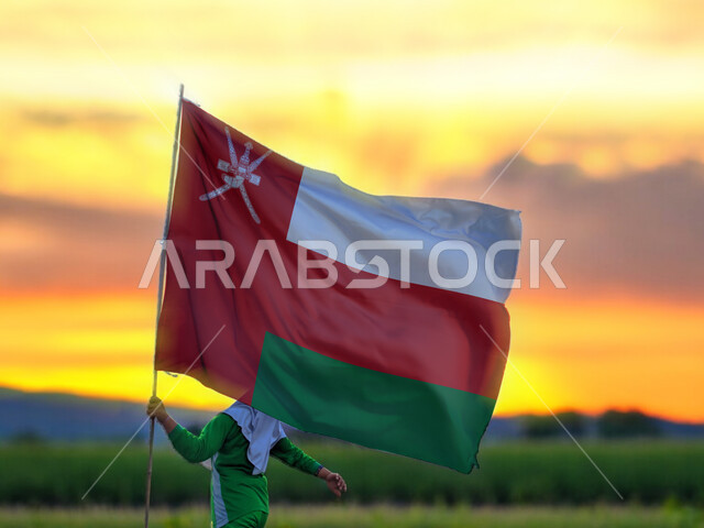 المشاركة بالأعياد والمناسبات الوطنية،, حب الوطن والانتماء إليه، ولد عربي خليجي عماني يحمل بيده علم سلطنة عمان، الاحتفال بذكرى اليوم الوطني العماني 18 نوفمبر،  إحياء ذكرى تأسيس الدولة 1775 م، الركوض في احدى المناطق العمانية، الاعتزاز والفخر بالرموز والراية