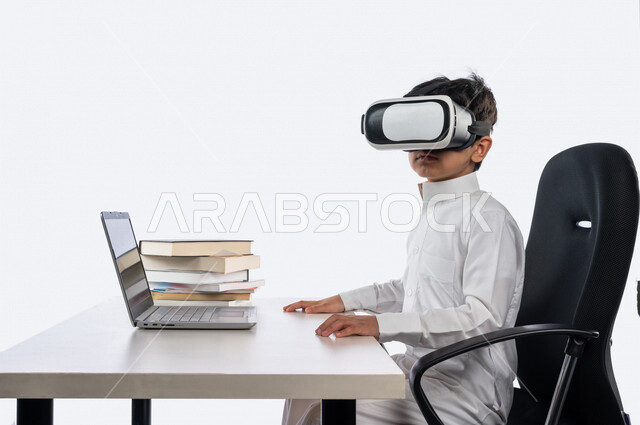 بورتريه لتلميذ عربي خليجي سعودي يرتدي الثوب السعودي التقليدي ، يرتدي نظارة واقع افتراضي ثلاثية الابعاد ، يدرس من خلال منصة تعليمية للتعلم عن بعد ، ايماءات و تعابير للوجه و اليدين مختلفة ، تأدية الواجبات المدرسية ، مفهوم التعليم عبر الانترنت