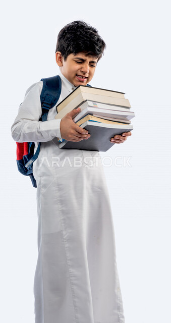 Portrait of a Saudi Arabian Gulf school student, wearing a school backpack, and wearing the traditional Saudi thobe, holding in his hand a group of textbooks, gestures and facial expressions and hands indicating fatigue, new school year, Saudi school