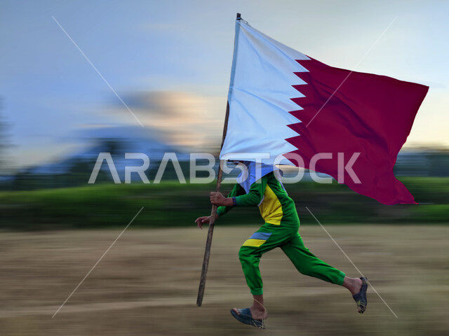 استذكار التاريخ والهوية الوطنية,  ذكرى اليوم الوطني القطري18 ديسمبر، ولد عربي يرفع بيده علم دولة القطر, الفخر والاعتزاز وحب الوطن والانتماء اليه، الركوض في احدى مناطق البلد 