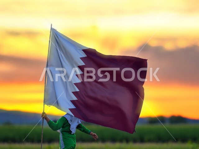 استذكار التاريخ والهوية الوطنية,  ذكرى اليوم الوطني القطري18 ديسمبر، ولد عربي يرفع بيده علم دولة القطر, الفخر والاعتزاز وحب الوطن والانتماء اليه، الركوض في احدى مناطق البلد 