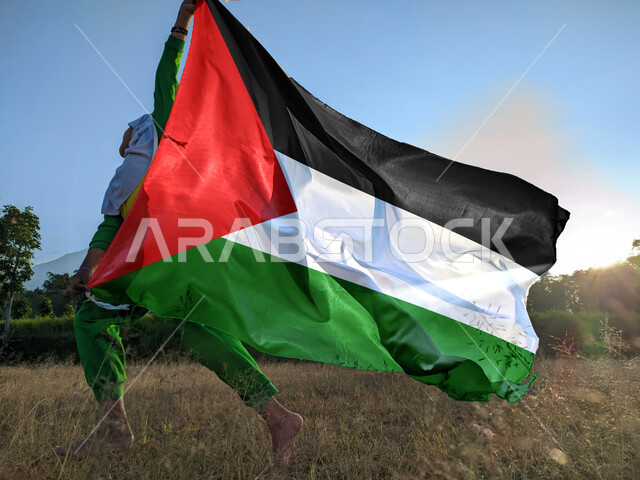 ذكرى احتفال اليوم الوطني الفلسطيني15نوفمبر، يوم بدينا1988م، حب الوطن والانتماء إليه، ولد عربي فلسطيني يرفع بيده علم الدولة الفلسطينية، المشاركة بالاعياد والمناسبات الوطنية، الركوض في احدى مناطق البلد