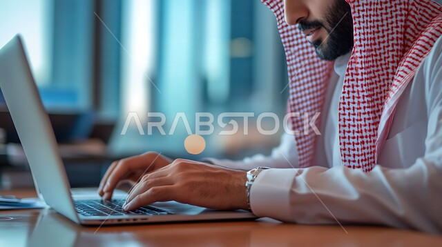 وظائف ومهن مكتبية سعودية، دمج العمل مع التكنولوجيا, إنجاز المهام المطلوبة، إدارة شؤون الشركة وتنظيمها عبر الاجهزة التقنية، صورة مقربة لرجل عربي خليجي سعودي يرتدي الزي التقليدي والشماغ يعمل على الحاسوب المحمول