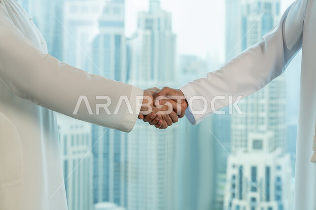 Concluding a new successful business agreement, friendships, acquaintances and building social relationships, a close-up of the hands of two Arab Gulf Emirati businessmen shaking hands, partnership in business and projects, a comfortable work environment in UAE companies