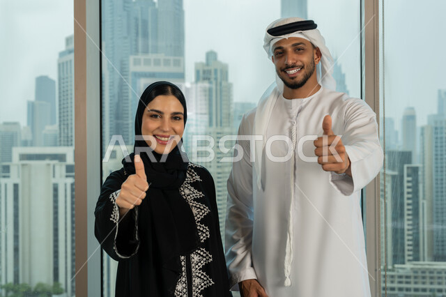 تعابير الجودة والامتياز، صورة مقربة لموظفين عربيين خليجيان اماراتيين يقفان باستقمامة يرفعان يديهما بايماءات القبول والموافقة، بيئة العمل المريحة في شركات الامارات، التفاهم والتعاون بين الزملاء لتحقيق أهداف الشركة
