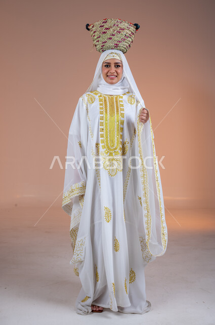 Looking at the camera with expressions of pride and honor, old popular professions and handicrafts, wearing the costumes of the Eastern Province, the day we started 1727 AD, a portrait of a smiling Saudi Arabian Gulf woman wearing a shayla and a nashal, placing a straw basket on her head, the anniversary of the founding of the first Saudi state on February 22, a colored background