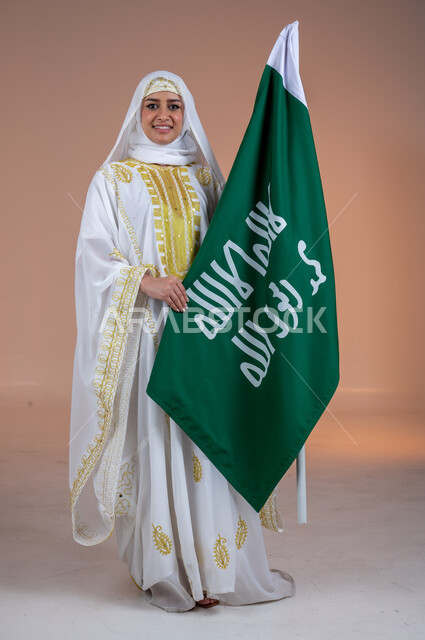 يوم العلم السعودي11 مارس، يوم بدينا 1727 م، ارتداء أزياء المنطقة الشرقية، بورتريه لإمرأة عربية خليجية سعودية مبتسمة ترتدي الشيلة والنشل تحمل بيدها علم يوم التأسيس، ذكرى تأسيس الدولة السعودية الأولى، الاحتفال بالمناسبات والأعياد الوطنية الشعبية، خلفية بنية