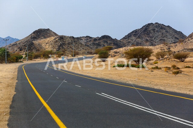 صورة للطريق السريع يمر بين الكثبان الرملية في الصحراء ، الرمال الذهبية الناعمة في صحراء السعودية