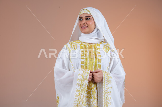مفهوم الانوثة والاهتمام بالمظهر الخارجي، بورتريه لامرأة عربية خليجية سعودية مبتسمة ترتدي الشيلة والنشل تنظر الى مكان ما بتعابير الفخر والاعتزاز، يوم بدينا١٧٢٧م، ارتداء أزياء المنطقة الشرقية في المناسبات الوطنية، ذكرى تأسيس الدولة السعودية الأولى٢٢فبراير، خلفية بنية