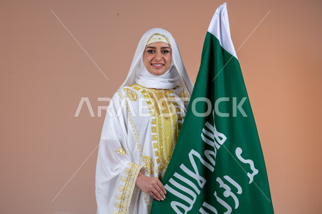 ذكرى تأسيس الدولة السعودية الأولى 22 فبراير، ارتداء أزياء المنطقة الشرقية في المناسبات والأعياد الوطنية، بورتريه مقرب لإمرأة عربية خليجية سعودية مبتسمة ترتدي الشيلة والنشل تحمل بيدها علم التأسيس، يوم بدينا 1727 م، خلفية ورية