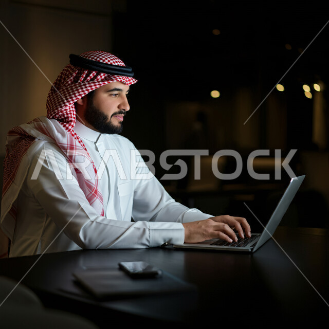 إدارة مهام العمل اليومية في مقر الشركة، مهن ووظائف سعودية، استخدام الأجهزة التقنية الحديثة، رجل عربي خليجي سعودي يرتدي الثوب التقليدي والشماغ يجلس في مكتبه يعمل على جهاز الحاسوب المحمول، تطوير الخطط والاسترتيجيات