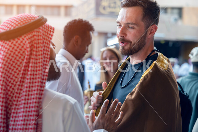 استقبال السياح الاجانب في الرياض في المملكة العربية السعودية، تقاليد وعادات شعبية في حسن الضيافة، تصوير مقرب لسواح اجانب يرتدون البشت السعودي المطرز، فتح ابواب السياحه السعودية، أماكن ومعالم سياحيه