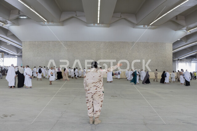 تقديم الخدمات و الحفاظ على أمان الحجاج و المعتمرين , أماكن ومعالم دينية إسلامية مقدسة في المملكة العربية السعودية , رجل أمن عربي خليجي سعودي يرتدي البدلة العسكرية يقوم بتوجيه الحجاج