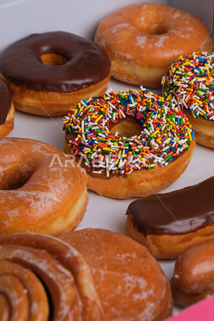 صورة مقربة لحلويات الدونات المتنوعة في علبة ورقية ، حلوى الدونات الشهية واللذيذة ، حلويات هشه طازجة