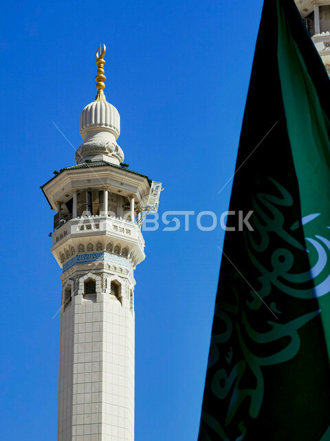 تصور مقرب لمئذنة الحرم المكي بجانبه علم المملكة العربية السعودية ، مكة المكرمة غرب المملكة العربية السعودية 