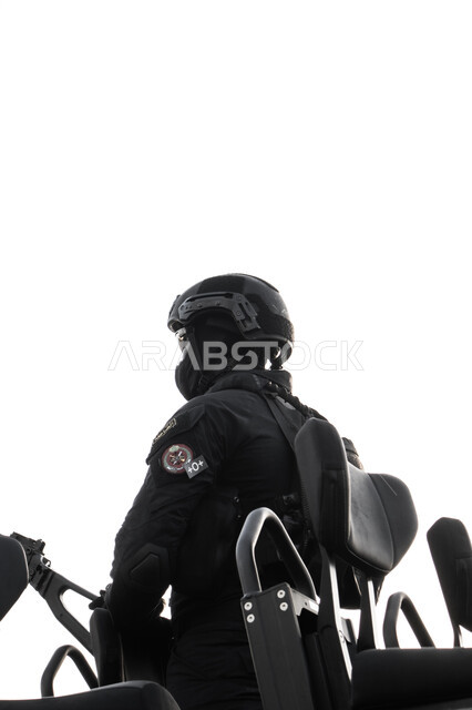 القوات العسكرية في المملكة العربية السعودية، العيون الساهرة لتوفير الأمن والأمان، بورتريه لجندي عربي خليجي سعودي يرتدي الزي العسكري الأسود الخاص بالقوات البحرية ويقف في آليه للجنود باستقامة وشموخ، حماية الوطن والدفاع عن الحدود في البر والبحر والجو، خلفية بيضاء