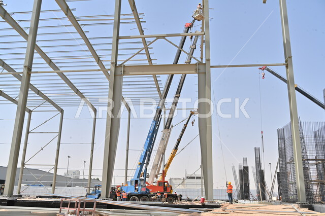  الجرافات والرافعات والسقالات العالية في موقع العمل, تنفيذ مخطط الإعمار وتشكيل الهيكل المعدني الأولي، أعمال البناء وصب الخرسانات ووضع الأساسات، الآلات والمعدات الثقيلة، مبنى قيد الانشاء في المملكة العربية السعودية, مفهوم الهندسة الانشائية والمعمارية