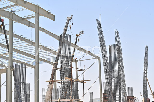 Implementation of the reconstruction plan and formation of the initial metal structure, construction works, pouring concrete and laying foundations, heavy machinery and equipment used in the work, cranes and high scaffolding, a building under construction in the Kingdom of Saudi Arabia, the concept of structural and architectural engineering