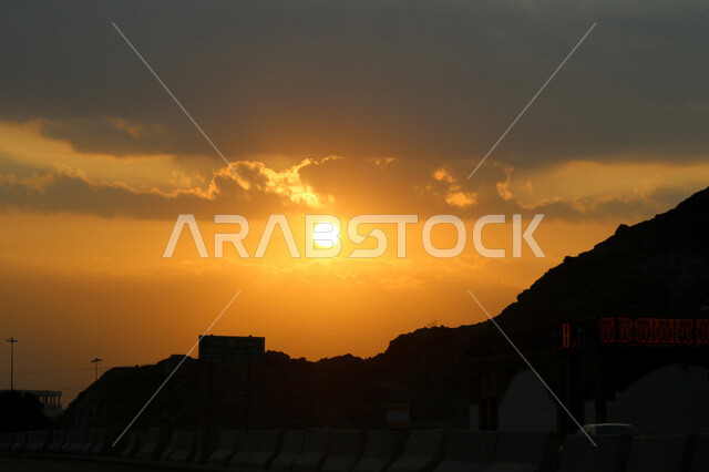 صورة توضيحية للمباني والجبال اثناء غروب الشمس، منظر طبيعي خلاب اثناء الغروب، جمال الطبيعة الجبلية مع غروب الشمس