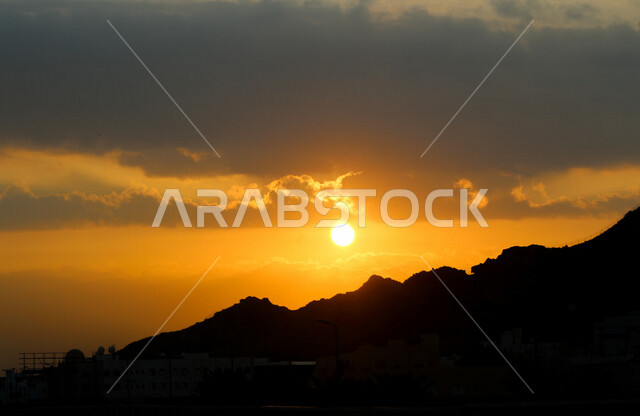 صورة توضيحية للمباني والجبال اثناء غروب الشمس، منظر طبيعي خلاب اثناء الغروب، جمال الطبيعة الجبلية مع غروب الشمس