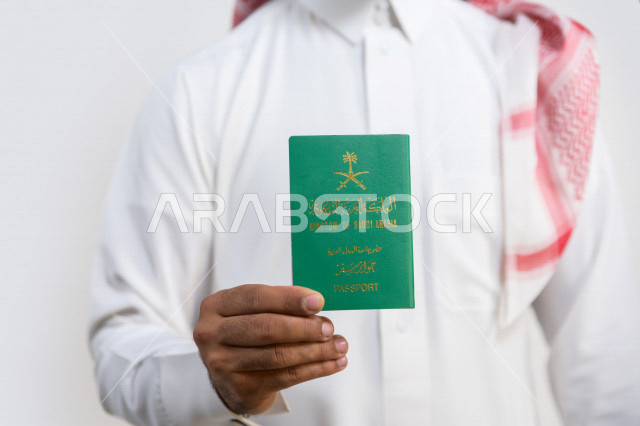 بورتريه لرجل عربي خليجي سعودي يحمل بيده جواز السفر السعودي ، وثيقة رسمية ، سفر المواطنين السعوديين دوليا ، اليوم الوطني السعودي ، الإحتفال بالعيد الوطني ، خلفية بيضاء