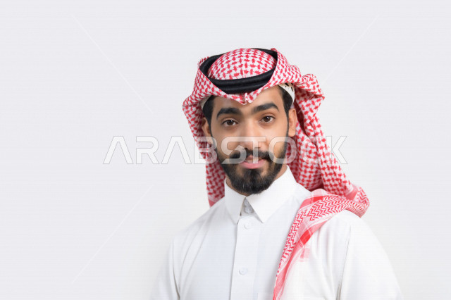 بورتريه لرجل عربي خليجي سعودي يرتدي الزي السعودي التقليدي بإيماءات تدل على السعادة ، خلفية بيضاء