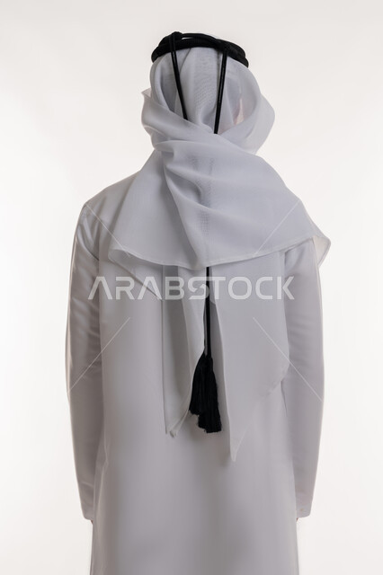 الأناقة والاهتمام بالمظهر الخارجي، بورتريه من الخلف لرجل عربي خليجي إماراتي يرتدي الكندورة الاماراتية والغترة يقف باستقامة وينظر إلى شي ما، مفهوم الرجولة والقوة، خلفية بيضاء