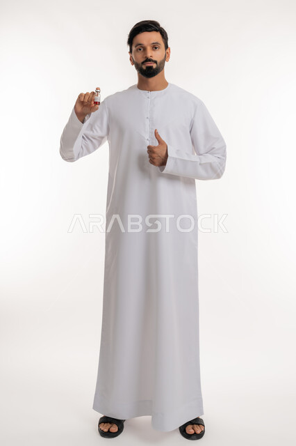 نشر الوعي الصحي للحد من انتشار الأمراض، علامة الجودة والامتياز، تلقي التطعيم ضد فايروس كورونا، بورتريه لرجل عربي خليجي إماراتي يرتدي الكندورة يحمل بيده جرعة لقاح كوفيد - 19 يرفع إبهامه للأعلى، اتباع إجراءات وزارة الصحة، الجسم بالطول الكامل، خلفية بيضاء