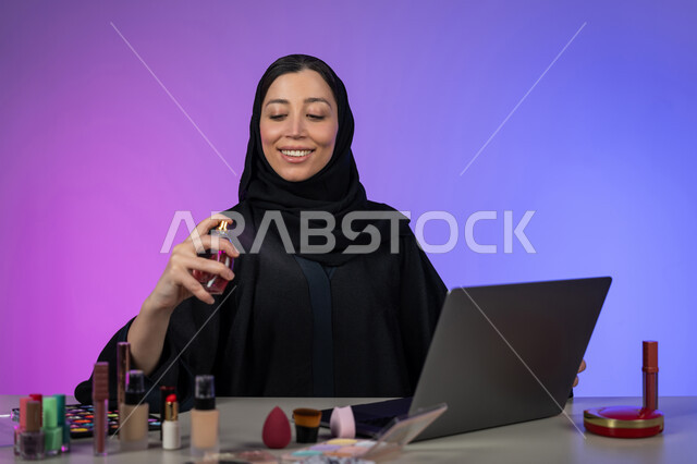 التسويق لمنتجات الروائح الوطنية الطيبة و الفاخرة، مفهوم الأناقة والاهتمام بالمظهر الخارجي، استخدام الزيوت العطرية الطبيعية، بورتريه لسيدة عربية خليجية إماراتية محجبة ترتدي عباءة سوداء تمسك بيدها زجاجة وتقوم برش العطر, شابة سعودية أنيقة تروج للعطور، خلفية ملونة