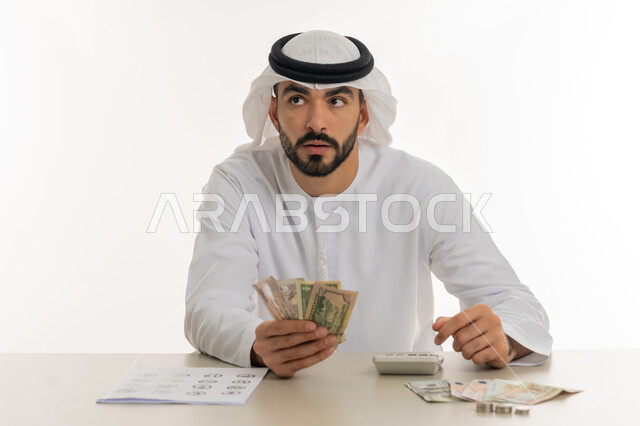 عرض الإصدار الجديد للنقود الاماراتية، العملة المتداولة في أسواق الامارات العربية المتحدة،  بورتريه لرجل عربي خليجي اماراتي يرتدي الكندورة والغترة يمسك بيده الفلوس، الأعمال الاقتصادية المالية، محاولة إدارة المصروف المنزلي بتدبر، السعي نحو الادخار، خلفية بيضاء