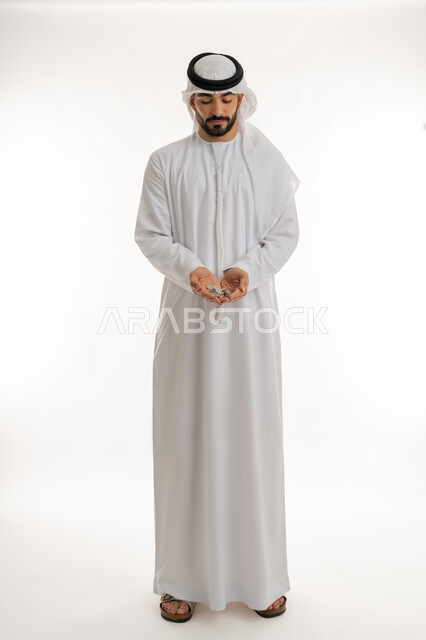 عرض الإصدار الجديد للنقود الاماراتية، العملة المتداولة في أسواق الامارات العربية المتحدة،  بورتريه لرجل عربي خليجي اماراتي يرتدي الكندورة والغترة يمسك بيده الفلوس، الأعمال الاقتصادية المالية، محاولة إدارة المصروف المنزلي بتدبر، السعي نحو الادخار، خلفية بيضاء