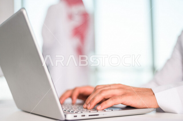 رجل اعمال عربي خليجي سعودي يستخدم جهاز الحاسوب المحمول ، العمل عن بعد ، انجاز مهام العمل ،تحقيق اهداف الشركة ، متابعة وتطوير العمل