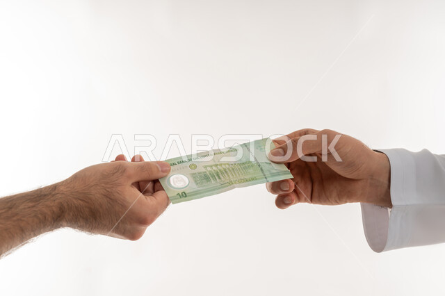 مفهوم الدفع نقدا، عملية تسديد النقود بواسطة الدراهم، استلام وتسليم الأمانات، العملة المتداولة في أسواق الامارات العربية المتحدة، الأعمال الاقتصادية المالية، بورتريه مقرب لرجل عربي خليجي اماراتي يرتدي الكندورة يقوم بدفع الفواتير وحسابات المشتريات، خلفية بيضاء