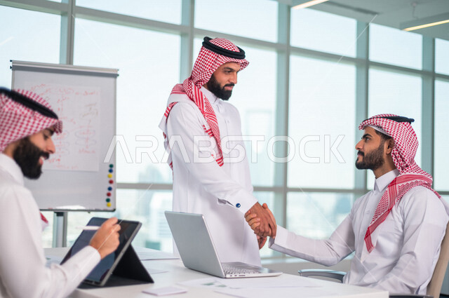 رجلان عربيان خليجيان سعوديان يتصافحان داخل الشركة  ، اتفاق عمل بين رجال الاعمال، صفقة ناجحة ، تعاون تجاري ، عمل جماعي مشترك