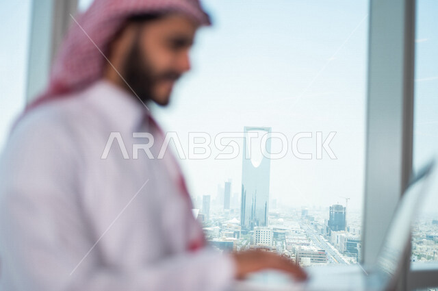 رجل اعمال عربي خليجي سعودي يستخدم جهاز الحاسوب المحمول ، العمل عن بعد ، انجاز مهام العمل ،تحقيق اهداف الشركة ، متابعة وتطوير العمل
