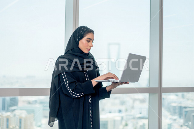سيدة اعمال عربية خليجية سعودية تستخدم جهاز الحاسوب المحمول ، العمل عن بعد ، انجاز مهام العمل ،تحقيق اهداف الشركة ، متابعة وتطوير العمل