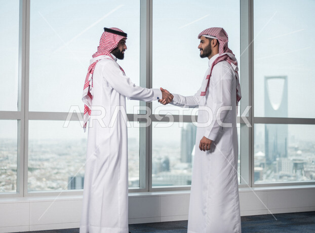 رجلان عربيان خليجيان سعوديان يتصافحان داخل الشركة  ، اتفاق عمل بين رجال الاعمال، صفقة ناجحة ، تعاون تجاري ، عمل جماعي مشترك