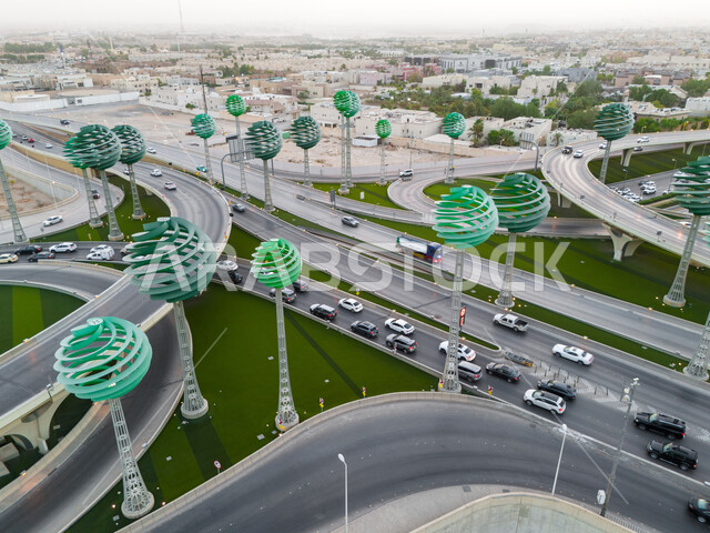 حركة المرور في شوارع وطرقات العاصمة في النهار، الفن الهندسي المعماري للمجسمات الفنية على شكل أشجار خضراء، معالم الرياض المشهورة، دوار عرقة على تقاطع طريق الملك عبد لله مع الملك خالد، تنشيط السياحة في المملكة العربية السعودية