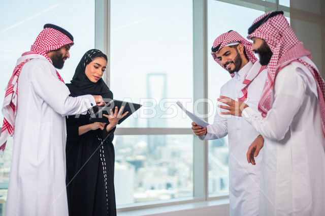مجموعة من الرجال الاعمال السعوديين داخل مقر الشركة ، مناقشة جدول الاعمال و المهام ، سكرتيرة عربية سعودية خليجية تعمل على تنظيم المهام و الاعمال و تدوين الملاحظات  عبر جهاز تقني، الوحدة والعمل الجماعي