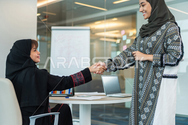 سيدتان عربيتان خليجيتان تتصافحان داخل الشركة ، اتفاق عمل بين سيدات الاعمال ، صفقة ناجحة ، تعاون تجاري ، عمل جماعي مشترك