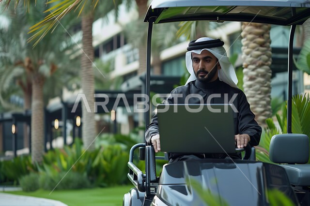 الاستمتاع بالاجواء الصيفيه أثناء انجاز المهام اليومية, رجل عربي خليجي سعودي يرتدي الزي التقليدي يجلس في عربة الغولف الكهربائية يستخدم جهاز الحاسوب المحمول, مفهوم العمل المتنقل في الهواء الطلق, دمج التقنيات الحديثة المتطورة في الحياة العملية