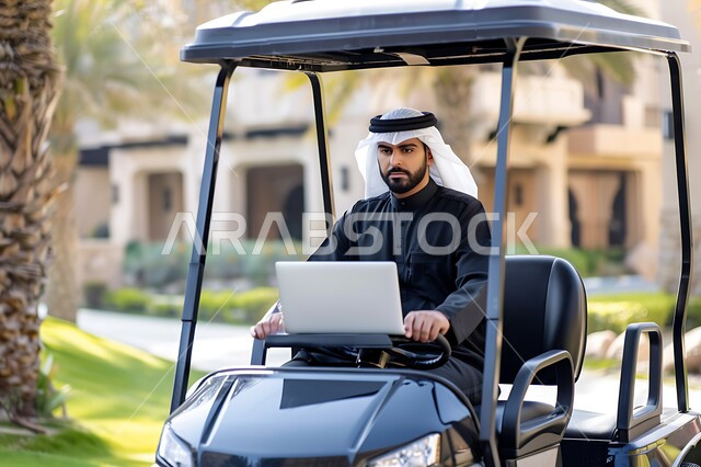 الاستمتاع بالاجواء الصيفيه أثناء انجاز المهام اليومية, رجل عربي خليجي سعودي يرتدي الزي التقليدي يجلس في عربة الغولف الكهربائية يستخدم جهاز الحاسوب المحمول, مفهوم العمل المتنقل في الهواء الطلق, دمج التقنيات الحديثة المتطورة في الحياة العملية