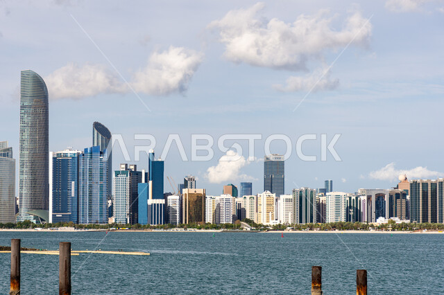 The development and urban progress of buildings and facilities in the UAE, the architectural art of towers and skyscrapers overlooking the sea, famous tourist attractions in the city of Abu Dhabi, places of attraction and attraction of tourists, the waterfront on the coast of the Arabian Gulf during the day