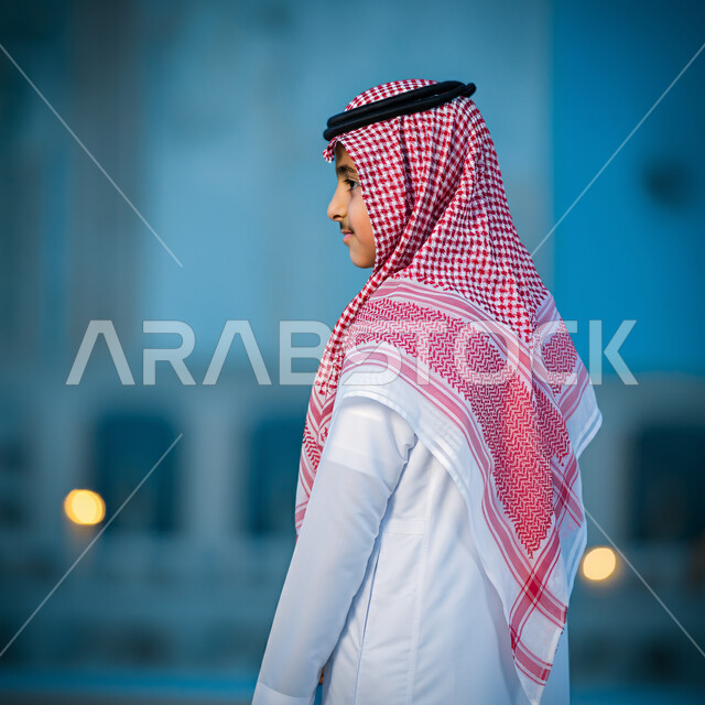 القوة والثقة بالنفس، صورة من الخلف لشاب عربي خليجي سعودي يرتدي الثوب التقليدي والشماغ يقف باستقامة ينظر إلى شيء ما، مفهوم الأناقة والاهتمام بالمظهر الخارجي